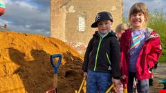 Ein Junge und ein Mädchen der Cts Kindertagesstätte St. Nikolaus zeigen ihre mit Sand vollbeladene Schubkarre. (Foto: SR/Simin Sadeghi)