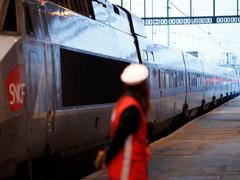 Eine Mitarbeiterin der Bahngesellschaft SNCF steht vor einem Zug (Foto: picture alliance / Christophe Ena/AP/dpa | Christophe Ena)
