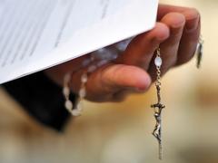 Ein Priester hält einen Rosenkranz und ein Schreiben in der Hand (Foto: dpa/Jochen Lübke)