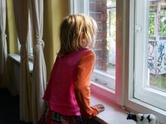 Kleines Mädchen schaut aus dem Fenster auf einen herunter gekommenen Spielplatz (Foto: picture-alliance/ dpa | Gero Breloer)