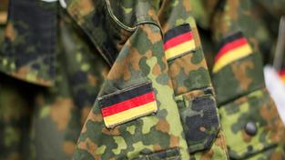 Jacken der Bundeswehr mit angenähter Deutschlandflagge hängen an einer Garderobe.  (Foto: dpa/Marcel Kusch)