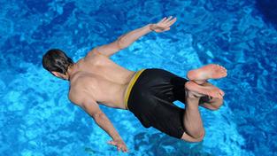 Ein Jugendlicher in langer Badehose springt in ein Schwimmbecken (Foto: picture alliance / dpa | Julian Stratenschulte)