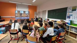 Schulklasse im Sitzkreis schaut sich gemeinsam ein Video an (Foto: Alex M. Groß)