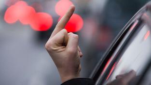 Einen sogenannten "Stinkefinger" zeigt ein Autofahrer aus seinem Auto. (Foto: picture alliance/dpa/dpa-Zentralbild | Jens Büttner)