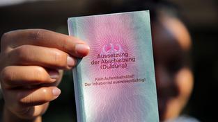 Eine junge Frau hält einen Ausweis für Geflüchtete in der Hand mit dem Titel: Aussetzung der Abschiebung (Duldung) (Foto: picture alliance/dpa | Wolfgang Kumm)