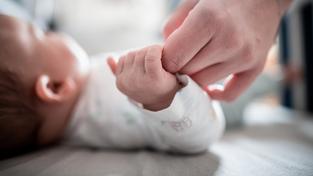 Ein Baby klammert sich an den Finger seiner Mutter.  (Foto: picture alliance/dpa | Fabian Strauch)