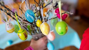 Zwei Kinder halten eine Vase mit Zweigen, an denen bunte Eier hängen (Foto: picture alliance/dpa | Sven Hoppe)