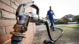 Ein Mitarbeiter eines Diesel- und Heizöl-Unternehmens geht zur Zapfpistole an einem Füllstutzen für die Heizöllieferung an einen Kunden in einem Einfamilienhaus (Foto: picture alliance/dpa | Christian Charisius)
