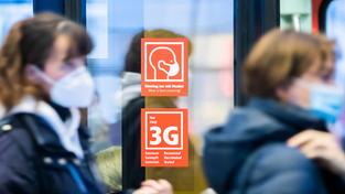 Straßenszene während der Corona-Pandemie. Hinweis auf Maskenpflicht und 3G-Regel. Passanten mit Mundschutz. (Foto: picture alliance/dpa | Christoph Soeder)