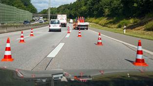 Bauarbeiter stellen orange-weiße Verkehrsleitkegel zum Einrichten einer Baustelle auf der Autobahn auf (Foto: picture alliance/dpa | Marcus Brandt)