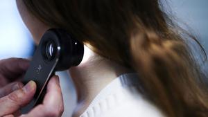 Ein Hautarzt untersucht bei einer Krebsvorsorgeuntersuchung eine Patientin mit einem Auflichtmikroskop (Foto: picture alliance/dpa/APA | Eva Manhart)