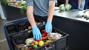 Ein ehrenamtlicher Helfer entpackt und sortiert Lebensmittel (Foto: picture alliance/dpa | Christian Charisius)