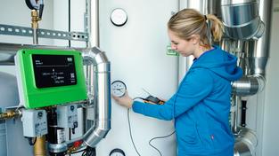 Eine Auszubildende für den Beruf der Anlagenmechanikerin Sanitär-Heizung-Klima steht vor einer Wärmepumpe (Foto: picture alliance/dpa | Uwe Anspach)