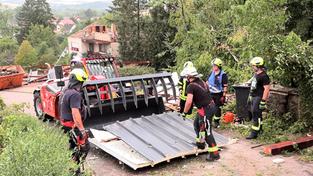Einsatzkräfte der Feuerwehr beseitigen nach einem Unwetter abgebrochene Gebäudeteile von einer Straße in Asweiler. (Foto: picture alliance/dpa | Thorsten Kremers)