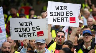 Teilnehmer der Kundgebung halten Schilder mit der Aufschrift „Wir sind es wert“ hoch (Foto: picture alliance/dpa | Hannes P Albert)