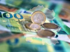 Geldscheine und Münzen liegen auf einem Tisch, darüber sind die Umrisse des Saarlandes gelegt (Foto: picture alliance/dpa | Monika Skolimowska)