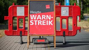 Ein Schild «Heute Warnstreik» steht auf der Straße vor einer Absperrung (Foto: picture alliance/dpa | Jan Woitas)