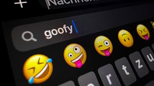 Im Display eines Smartphones ist im Suchfeld für Smileys das Wort «goofy» (komisch, tollpatschig) zu lesen. (Foto: picture alliance/dpa | Carla Benkö)