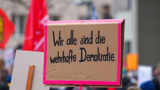 Ein Plakat „Wir alle sind die wehrhafte Demokratie“ auf einer Kundgebung gegen Rechtsextremismus, an der auch Gewerkschaften teilnehmen (Foto: picture alliance/dpa | Andreas Arnold)