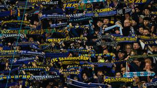 Fans von Saarbrücken stehen mit ihren Schals auf der Tribüne. (Foto: picture alliance/dpa | Uwe Anspach)