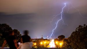 Zwei Personen beobachten bei Gewitter einen Blitz am Himmel über der Stadt (Foto: picture alliance/dpa | Peter Kneffel)