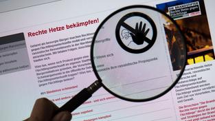 Lupe vergrößert Verbotsschild auf einer Internetseite zu rechter Hetze im Internet (Foto: dpa/Arno Burgi)