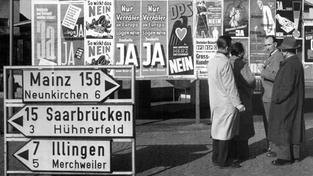 Passanten diskutieren 1955 vor einer Anschlagtafel über die bevorstehende Saarabstimmung. (Foto: dpa)