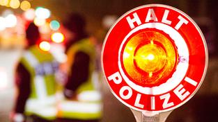 Eine Polizist hält eine Kelle mit der Aufschrift "Halt Polizei" nach oben. (Foto: picture alliance / dpa | Daniel Bockwoldt)