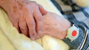 Eine pflegebedürftige Frau trägt einen Notknopf am Handgelenk (Foto: picture alliance/Britta Pedersen/dpa-Zentralbild/dpa)