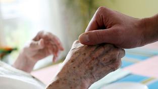 Zwei Hände halten sich gegenseitig am Krankenbett (Foto: picture alliance / Oliver Berg/dpa | Oliver Berg)