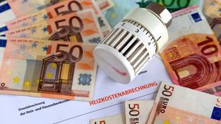 Geldscheine und ein Heizungsthermostat liegen auf einer Heizkostenabrechnung (Foto: picture alliance / dpa | Jens Büttner)
