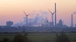 Windräder drehen sich neben einem Stahlwerk im Wind (Foto: IMAGO / blickwinkel)