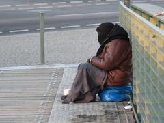 Ein Obdachloser, eingemummt in eine dicke Jacke, Mütze und Decke, sitzt bei bissiger Kälte im Freien. (Foto: IMAGO / Winfried Rothermel)
