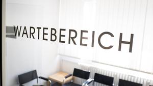 Auf einer Tür zu einem leeren Wartebereich für Patienten steht 