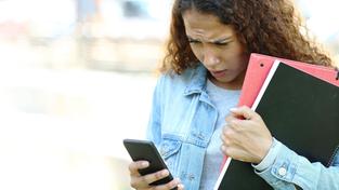 Eine jugendliche Schülerin schaut mit Stirnrunzeln auf ihr Smartphone (Foto: IMAGO / Panthermedia)