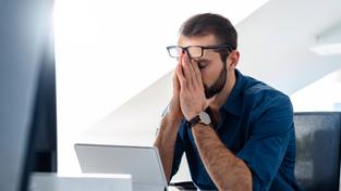 Ein Mann ist mit seiner Arbeit im Büro überlastet (Foto: IMAGO / Westend61)