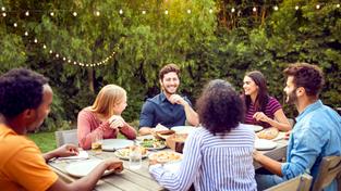 Menschen sitzen an einem Gartentisch zusammen (Foto: IMAGO / Shotshop)