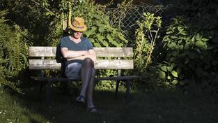 Ein älterer Herr sitzt mit einem Hut auf einer Bank im Grünen in der Sonne (Foto: IMAGO / photothek)