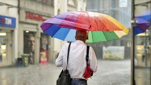 Ein Mann mit großem Regenschirm läuft durch den Regen (Foto: IMAGO / ABACAPRESS)