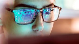 Eine Person sitzt vor dem Computer, Bildschirminhalt spiegelt sich auf seiner Brille (Foto: IMAGO / Westend61, Farbkorrektur: SR)