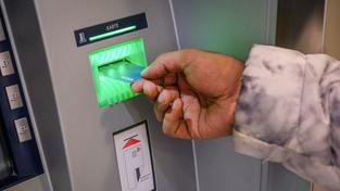 Eine Hand mit einer Bankkarte vor einem Geldautomaten (Foto: IMAGO / epd)