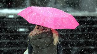 Fußgängerin schützt sich mit einem Regenschirm vor den Schneeflocken. (Foto: Imago/Ralph Peters)