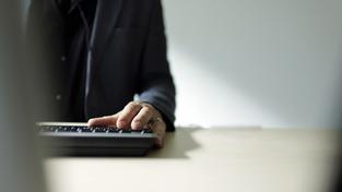 Ein Mann steht am Schreibtisch vor einem Computer (Foto: IMAGO / photothek)