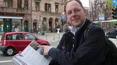 Der Geograph Markus Philipp mit seinem Buch „Saarbrücker Spurensuche“ am Rathausplatz (Foto: Peter Weitzmann)