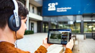 Junger Mann mit Tablet liest SR-Nachrichten vor dem SR-Gebäude (Foto: Sebastian Knöbber/SR)