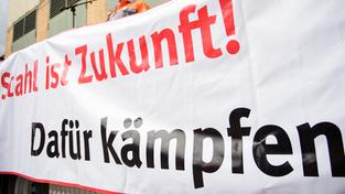 Mit einem Banner protestieren Mitarbeiter der Stahlindustrie (Foto: picture alliance / Oliver Dietze/dpa)