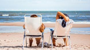Zwei Urlauber liegen am Strand in der Sonne (Foto: unsplash / Ezequiel Garrido)