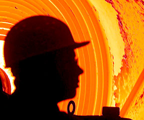 Kopf eines Hüttenarbeiters vor einem glühenden Stahlcoil