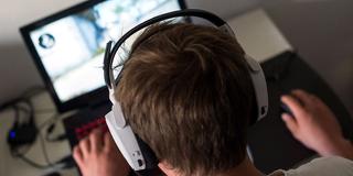 Symbolbild: Ein Junge sitzt an einem Laptop und spielt darauf ein Spiel. (Foto: dpa)