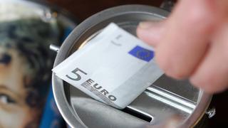 Eine Hand steckt einen Fünf-Euro-Schein in eine Spendendose (Foto: dpa/Bernd Thissen)